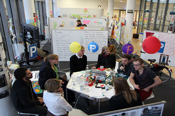 Leute am Tisch in einem Design THinking Workshop Teamspace