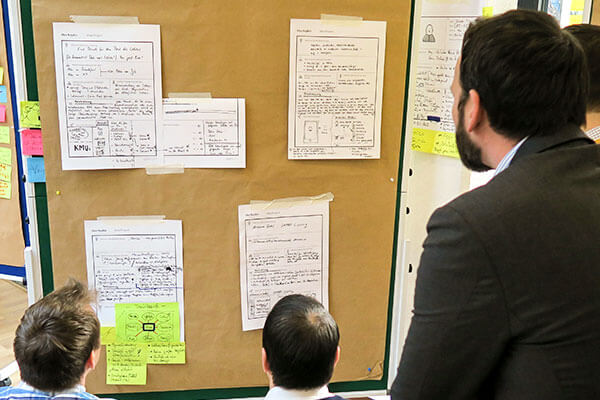 Männer schauen auf Notizen während eines Design Thinking Workshops